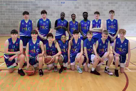 Eine Gruppe junger Basketballspielerinnen und Basketballspieler posiert in der Turnhalle des St. Mel’s College vor einer Backsteinwand.