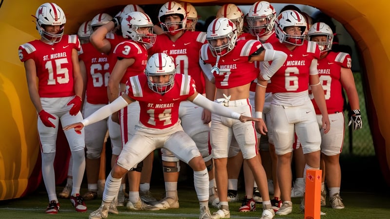 Eine Gruppe von jungen Fußballspielern in roten Trikots steht in einem Umkleideraum der St. Michael Catholic Secondary School.