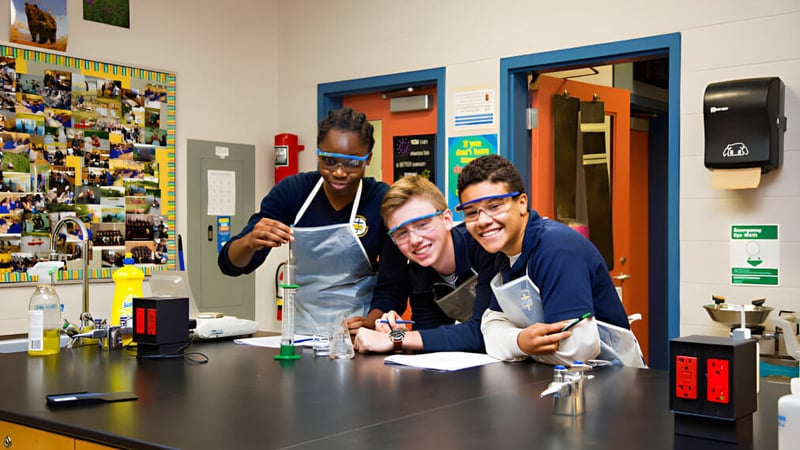 Eine Gruppe von Schülerinnen und Schülern versammelt sich im Labor der St. Michael Catholic Secondary School um einen Tisch mit wissenschaftlichen Geräten.