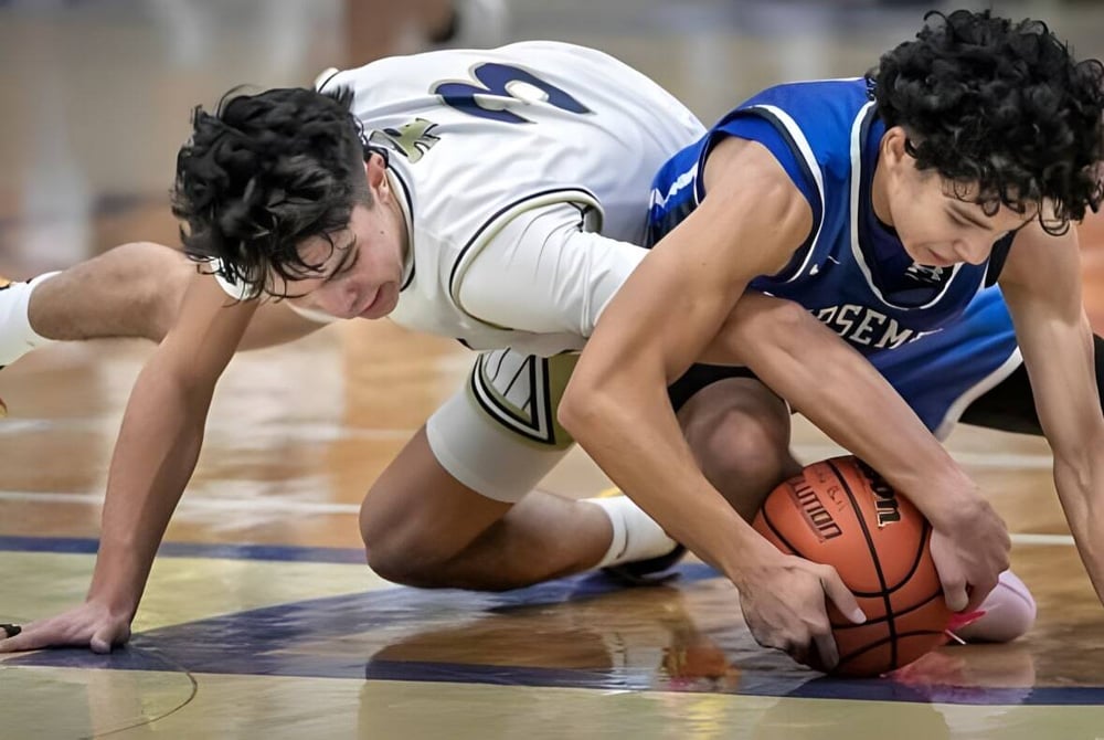 Zwei Basketballspieler kämpfen intensiv um den Ball auf dem Spielfeld der St. Michael's Regional High.
