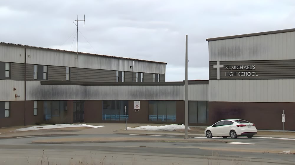 Das große graue Industriegebäude vor dem Parkplatz der St. Michael's Regional High ist zu sehen.