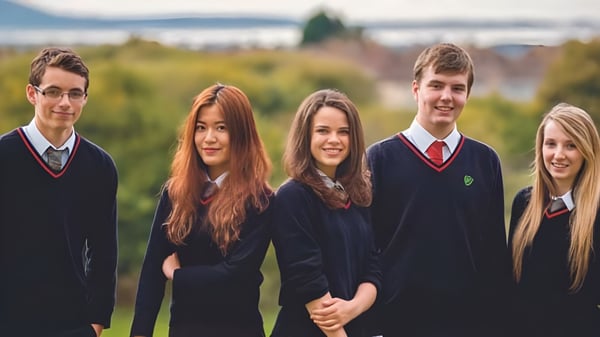 Eine Gruppe von fünf Schülern in Schuluniformen steht vor einer Berglandschaft auf dem Gelände der St. Michael’s School.