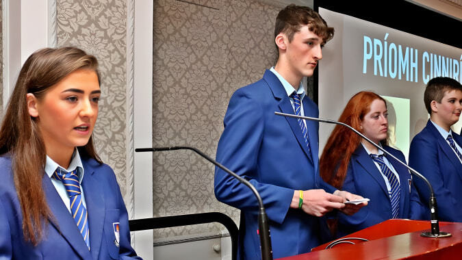 Eine Gruppe Schülerinnen und Schüler des St. Mogues College steht am Rednerpult bei einer Priorni Dining Veranstaltung.