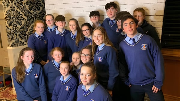 Eine Gruppe von Schülern in blauen Schuluniformen posiert vor einer gemusterten Wand auf dem Gelände des St. Mogues College.