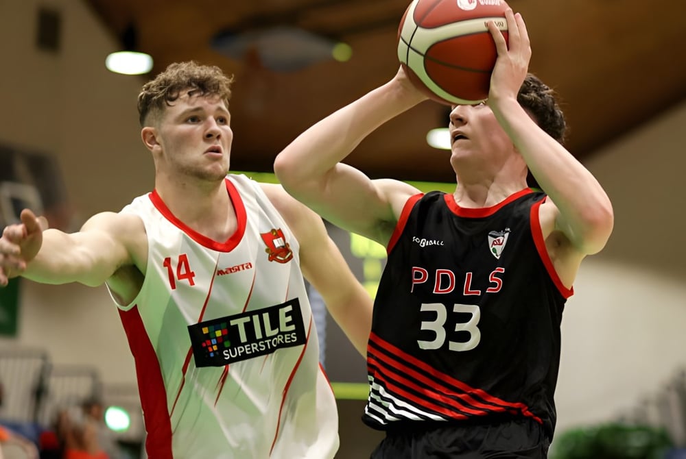 Zwei Schüler von St. Muredach's College kämpfen um den Ball während eines Basketballspiels auf dem Spielfeld.