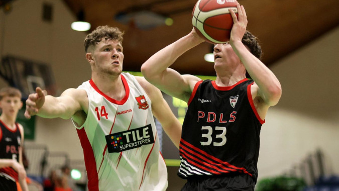Zwei Basketballspieler kämpfen während eines Spiels auf dem Basketballfeld von St. Muredach's College um den Ball.