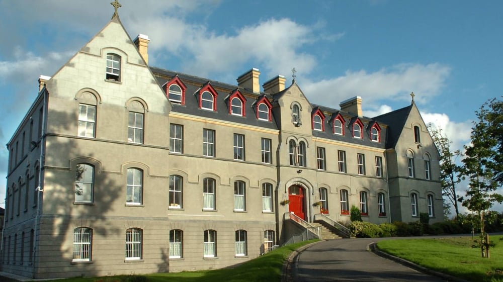 Das mehrstöckige Gebäude von St. Muredach's College ist von üppigem Grün umgeben und ein geschwungener Weg führt zum Eingang.