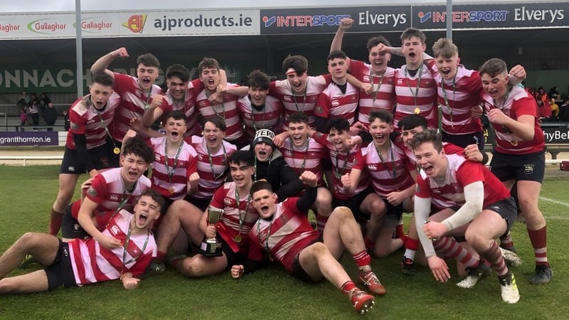 Eine Gruppe von Rugbyspielern des St. Muredach's College feiert gemeinsam auf dem Sportfeld.