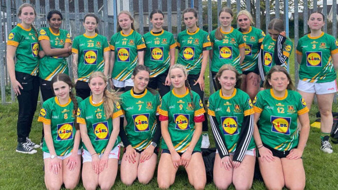 Eine Gruppe junger Sportlerinnen in grünen und gelben Uniformen posiert auf dem Außengelände von St. Patricks College in Cork.