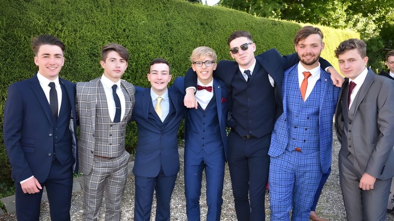 Eine Gruppe von Personen steht im Garten des St. Patrick's College bei einer formellen Veranstaltung.