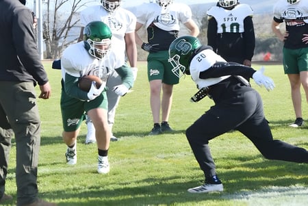 Eine Gruppe von Fußballspielern der St. Patrick's High School trainiert auf einem Rasenplatz.