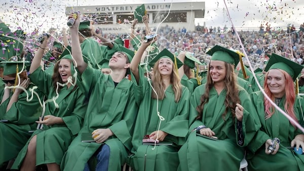 Absolventinnen und Absolventen der St. Patrick's High School feiern im grünen Gewand mit Konfetti.