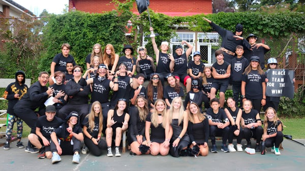 Eine große Gruppe Schülerinnen und Schüler der St. Patrick’s High School in Québec City posiert vor einem Backsteingebäude mit Grünflächen.