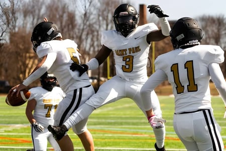 Eine Gruppe von Footballspielern in weißen Trikots spielt auf dem Sportfeld der St. Paul Catholic High School.