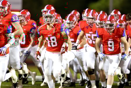 Eine Gruppe Fußballspieler der St. Paul High School steht nachts auf dem Spielfeld eines Stadions.