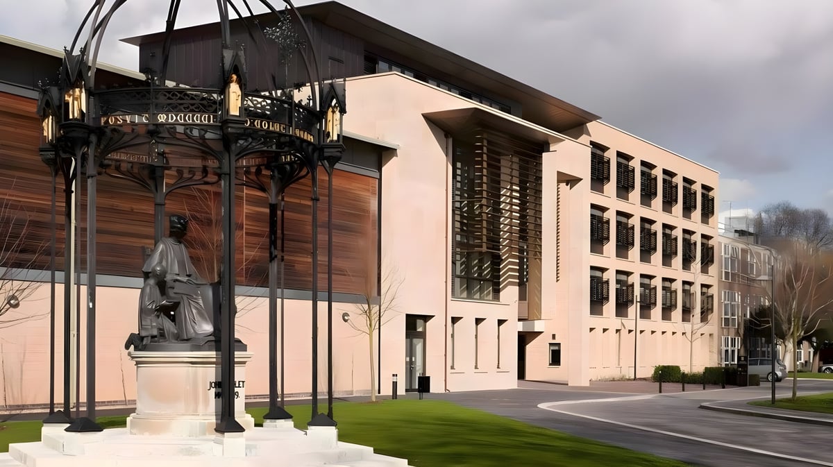 Das historische Gebäude der St. Paul’s School mit einer Statue im Vordergrund und städtischer Umgebung.