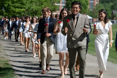 Eine Gruppe von Personen geht auf einem von grünen Pflanzen umgebenen Weg auf dem Campus der St Paul’s School.
