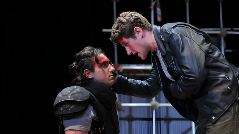 Zwei Personen interagieren intensiv vor dunklem Hintergrund auf dem Gelände der St. Paul’s School.