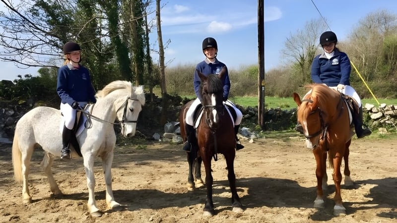 Drei Schüler der St. Paul's Secondary in Galway reiten auf einem Waldweg mit Bäumen und Grün im Hintergrund.