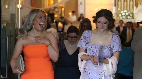 Zwei Frauen in formeller Kleidung gehen gemeinsam an einem Event auf dem Gelände der St. Paul's Secondary School in Kildare vorbei.