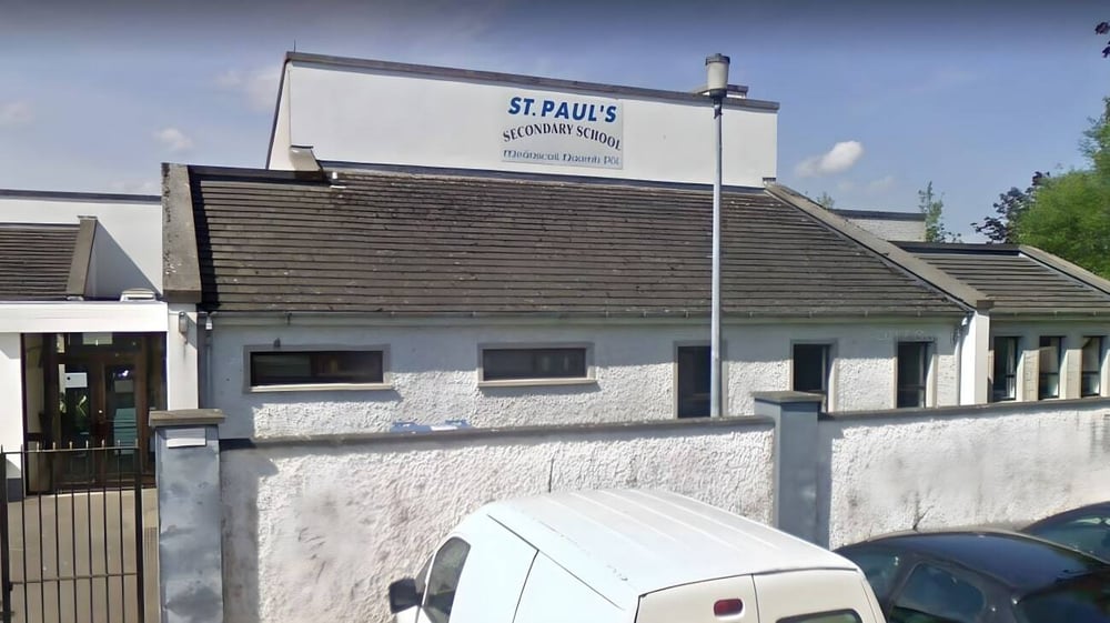 Das zweistöckige Gebäude der St. Paul's Secondary School in Kildare mit beschildertem Dach und einem Parkplatz im Vordergrund.
