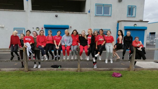 Eine Gruppe Schülerinnen der St. Paul's Secondary School in passenden Sportkleidungen steht vor einem Gebäude mit blauen Akzenten.