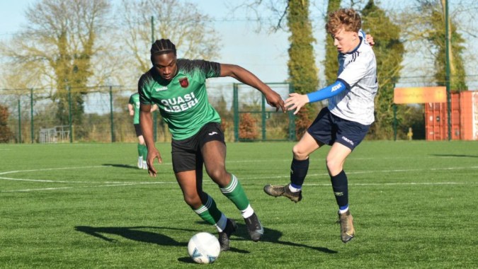 Zwei Fußballspieler der St. Peter's Community School kämpfen auf einem Spielfeld um den Ball.