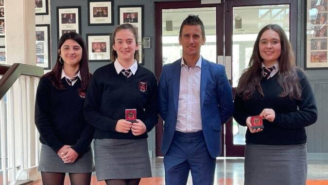 Vier Personen, darunter Schülerinnen und Schüler, stehen gemeinsam im Eingangsbereich der St. Peter's Community School.