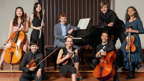 Eine Gruppe von Musikerinnen und Musikern der St. Peter’s High School spielt verschiedene Instrumente auf einer Bühne mit Holzhintergrund.