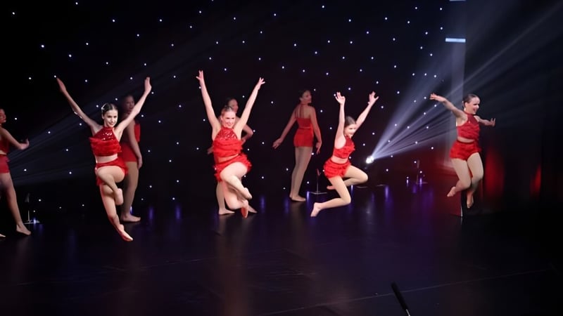 Eine Gruppe Tänzer in roten Kostümen führt auf der Bühne der St. Peters School vor einem sternenklaren Himmel eine Choreografie auf.