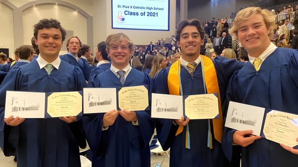 Vier Absolventen der St. Pius X High School in Talaren halten ihre Diplome bei einer Abschlussfeier.