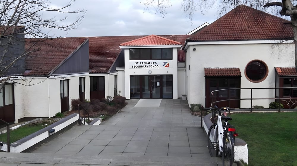 Das Gebäude der St. Raphaela’s Secondary School mit rotem Ziegeldach und einem Fahrrad vor dem Eingang.