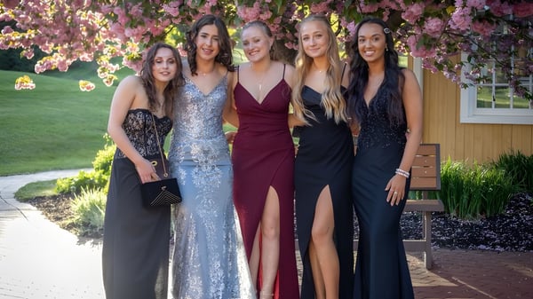 Fünf Schülerinnen von St. Raphaela’s Secondary School stehen gemeinsam in einem Garten mit blühenden Bäumen.