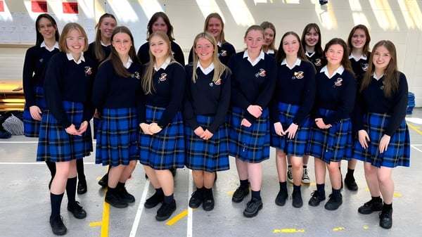 Eine Gruppe von Schülerinnen der St. Raphaela’s Secondary School steht gemeinsam vor einem Gebäude mit großen Fenstern.