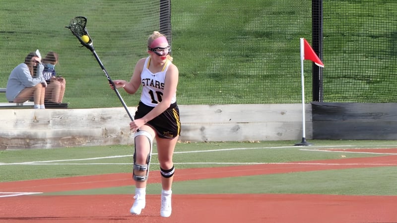 Eine Person in rosa Trikot steht auf dem Baseballfeld des St. Teresa’s College vor Gras und rotem Boden.