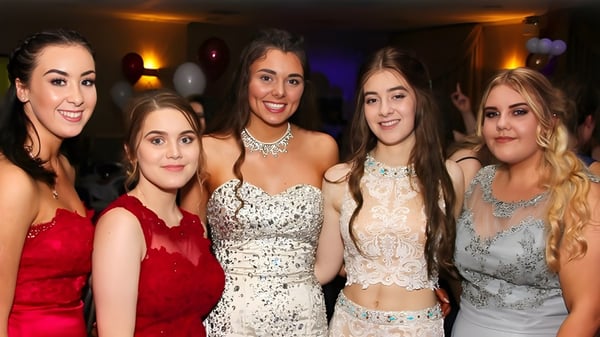 Fünf Schülerinnen der St. Thomas More School posieren in formeller Kleidung bei einer Feier.