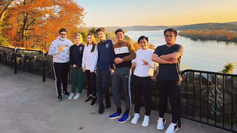 Eine Gruppe Schüler steht auf einem Geländer mit Blick auf die herbstliche Landschaft mit See und Bergen an der St. Thomas More School.