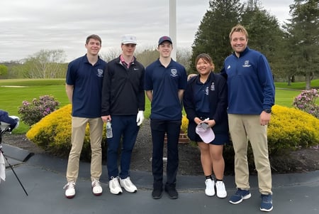Eine Gruppe von Schülern der St. Thomas More School steht gemeinsam im Park mit Bäumen und Grünflächen im Hintergrund.