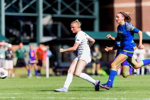 Schüler spielen ein Fußballspiel auf dem Sportplatz der St. Tiernan’s Community School mit Zuschauern im Hintergrund.