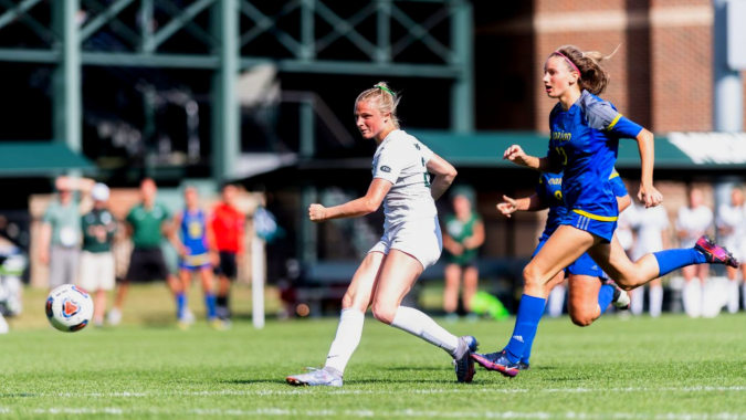 Zwei Fußballspieler in weißen und blauen Uniformen spielen auf dem Spielfeld der St. Tiernan’s Community School.