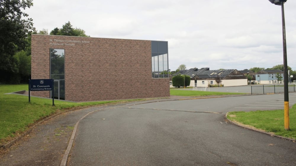 Das Backsteingebäude mit Glasfassade der St. Tiernan’s Community School ist von einem gepflasterten Weg und Grünflächen umgeben.