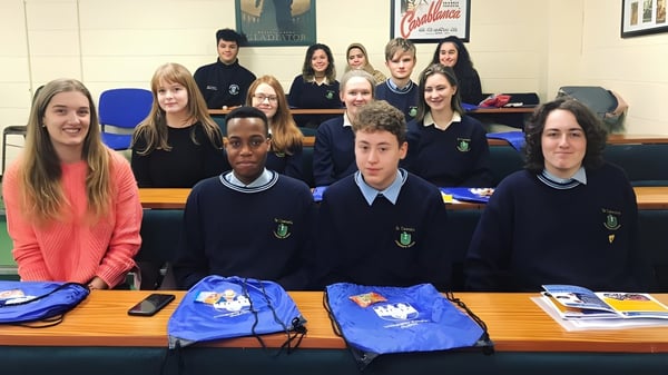 Schüler der St. Tiernan’s Community School sitzen in Schuluniformen an Tischen mit Schulmaterialien.