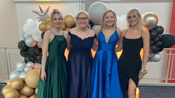 Vier Schülerinnen der St. Timothy High School posieren vor einem Hintergrund aus bunten Luftballons.