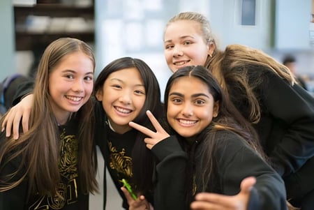 Eine Gruppe lächelnder Schülerinnen posiert gemeinsam auf dem Campus der St. Timothy High School.