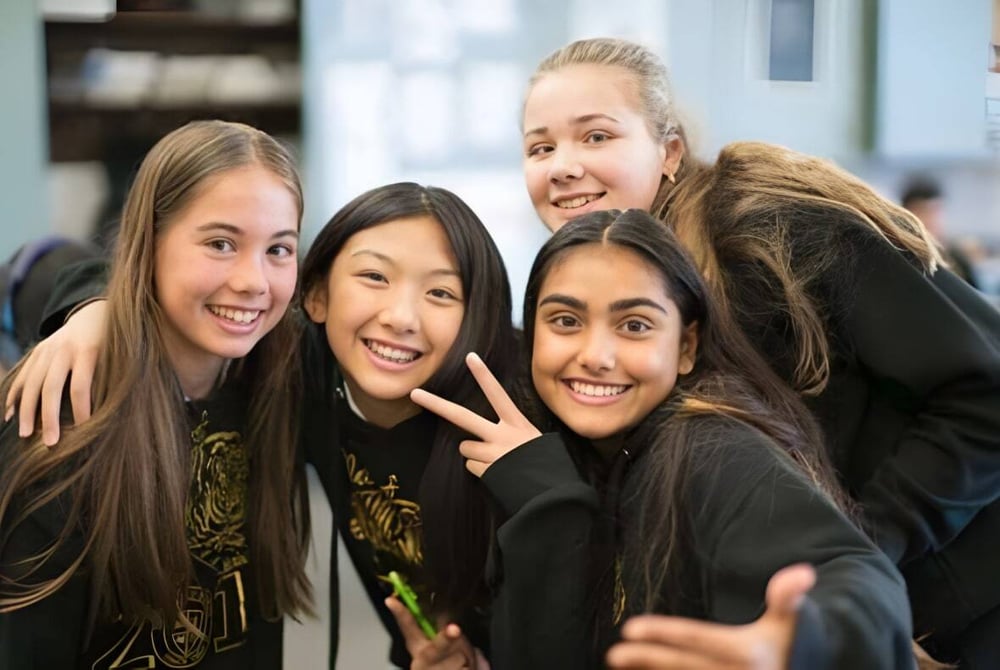 Eine Gruppe lächelnder Schülerinnen posiert gemeinsam auf dem Campus der St. Timothy High School.