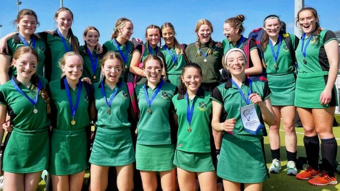Schülerinnen der St. Vincent's Secondary School feiern gemeinsam auf dem Sportfeld bei blauem Himmel.
