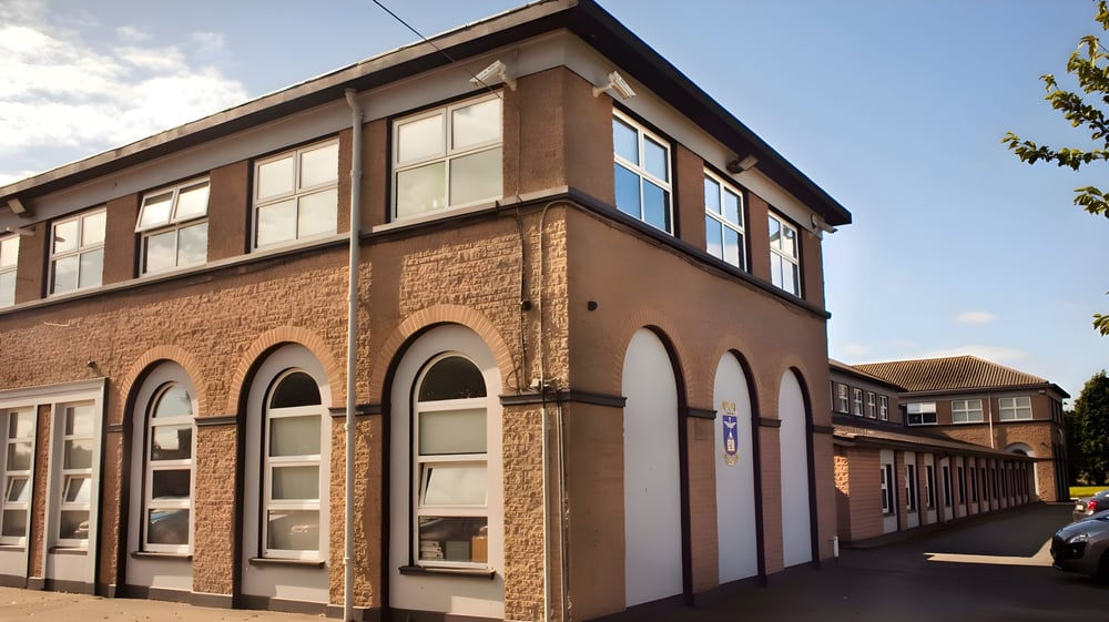 Das mehrstöckige Backsteingebäude der St. Vincent's Secondary School in Dublin mit Bögen in den Fenstern und umgeben von Bäumen.