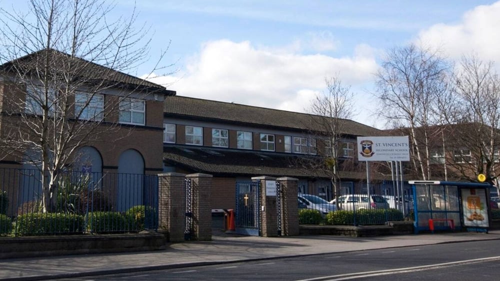 Das mehrstöckige Backsteingebäude der St. Vincent's Secondary School mit bogenförmigen Fenstern und einem ziegeldach ist von Bäumen und einer gepflasterten Straße umgeben.