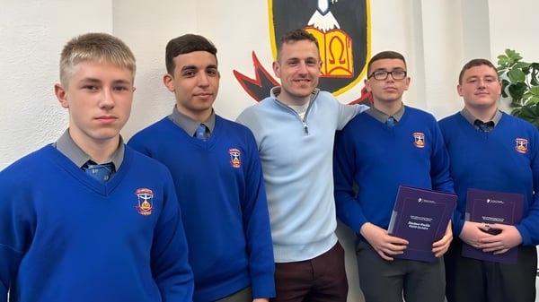Eine Gruppe von Schülern der St. Vincent's Secondary School in Dublin steht vor einer Wand mit einem Wappen.