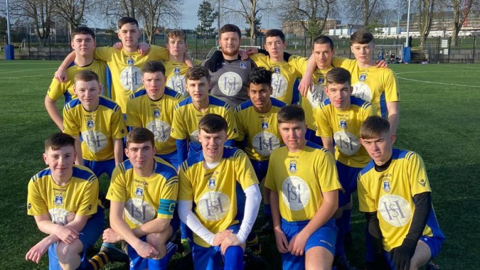 Eine Gruppe junger Fußballspielerinnen und -spieler der St. Vincent's Secondary School in Dublin posiert auf dem Sportplatz.